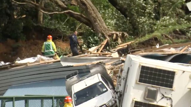 A police officer with dog searches for people near the site of a landslide at the base of Mount Maunganui on New Zealand’s North Island 