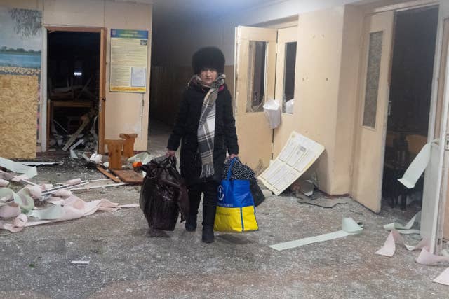 A resident leaves her home in a damaged building following a Russian drone attack in Kharkiv,