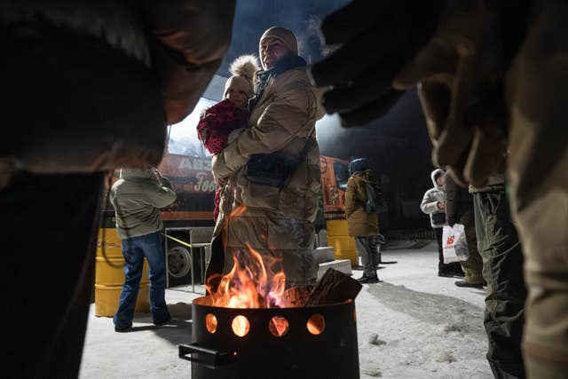 People keep warm beside a makeshift fire
