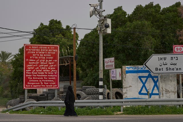 A woman walks down a road in the Jordan Valley, West Bank