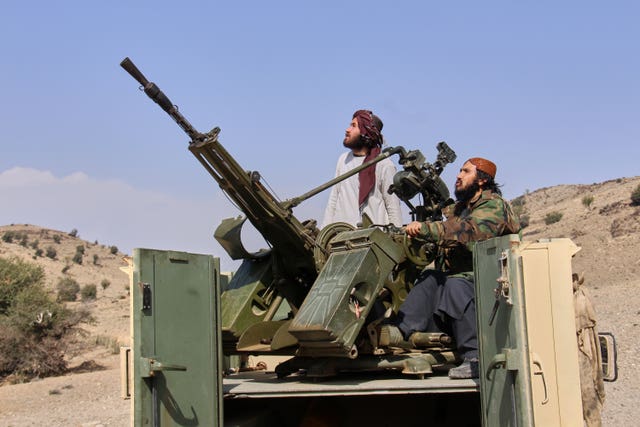 Taliban fighters look up while manning an armed pick-up truck at the border with Pakistan