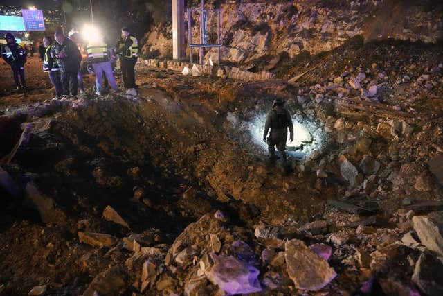 Israeli security forces inspect a damaged road after a missile launched from Iran struck Jerusalem on Sunday