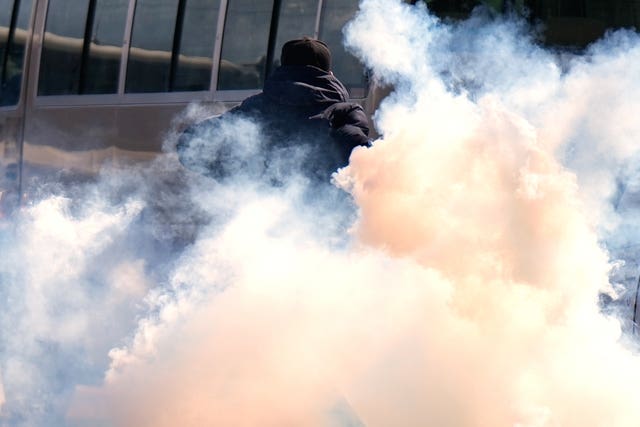 A man shrouded in tear gas on a street