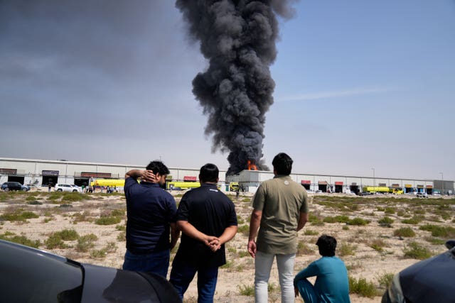Residents watch as the flames and a black plume of smoke rises over Sharjah City in the United Arab Emirates