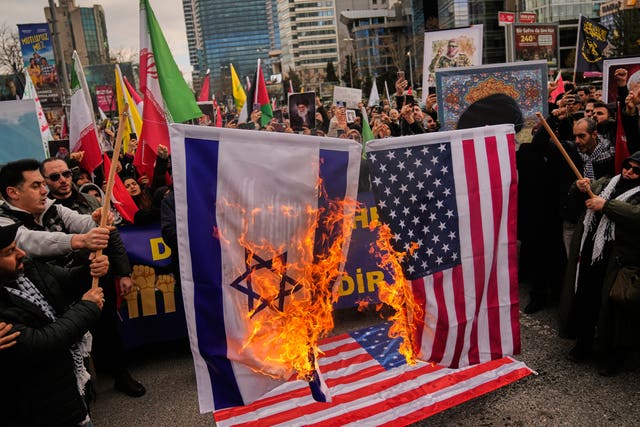 Demonstrators burn Israeli and American flags during a protest outside the Israeli consulate in Istanbul in Turkey 