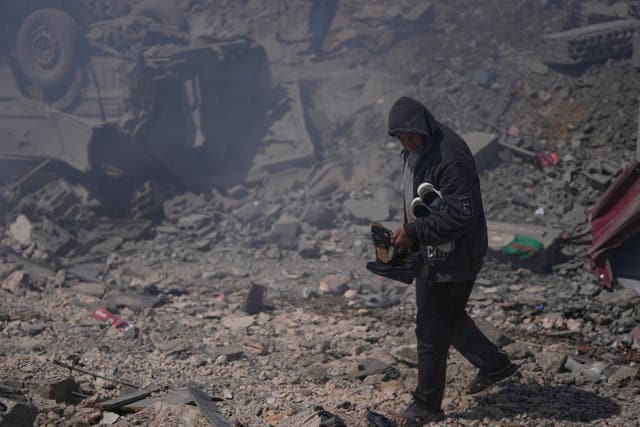 A man carrying shoes from a bombed house in Lebanon