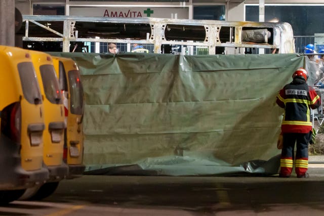 Firefighters and police officers install barriers to secure the area where a bus caught fire in Kerzers, Switzerland