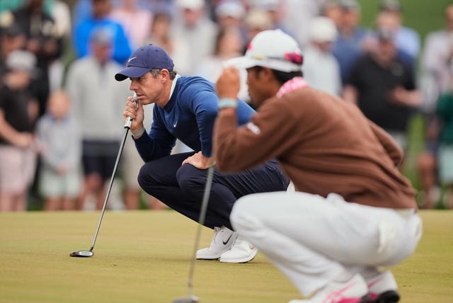 Rory McIlroy, left, of Northern Irelan and Hideki Matsuyama, front, of Japan work on the 11th green