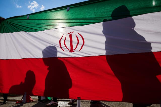 Protesters cast shadows onto an Iranian state flag during an Al Quds Day (Jerusalem Day) rally in Toronto