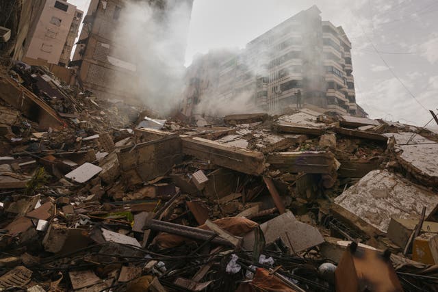 Smoke rises from a large pile of rubble from destroyed buildings