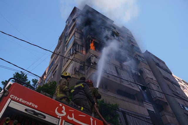 Firefighters spray water on a burning residential building following an Israeli air strike in central Beirut, Lebanon