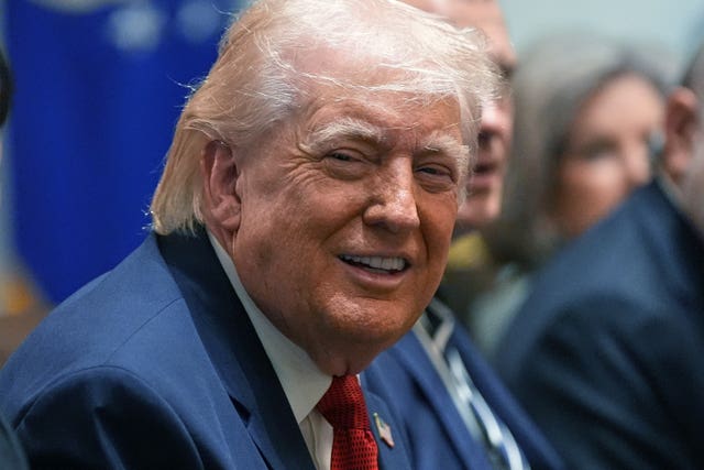 Donald Trump laughing while sitting at the cabinet table