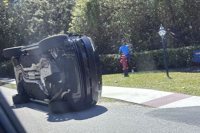 Golfer Tiger Woods stands by his overturned vehicle in Jupiter Island