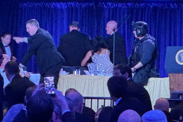 US Secret Service agents surround President Donald Trump as he is taken from the stage after a shooting incident outside the ballroom during the White House Correspondents Dinner (Mark Schiefelbein/AP)