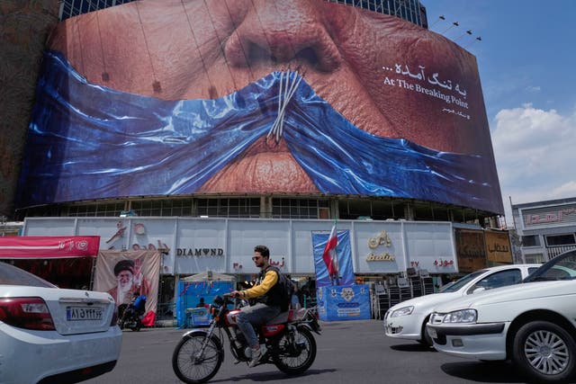 a billboard showing an image of the Strait of Hormuz and sewn lips of US President Donald Trump