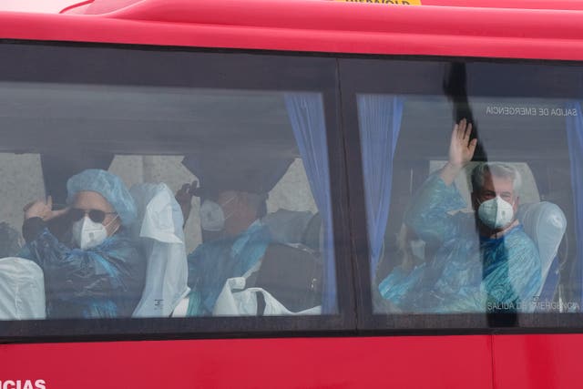 Passengers wave inside a bus after being disembarked from the hantavirus-stricken cruise ship