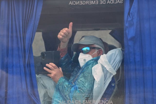 A passenger gives a thumbs-up inside a bus after being disembarked from the MV Hondius