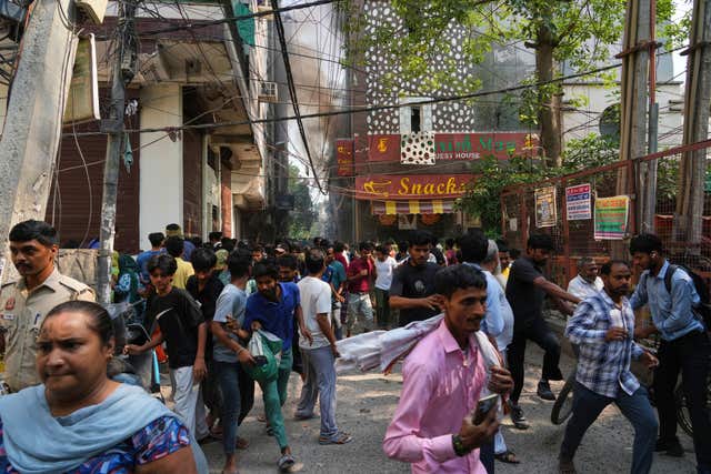 People run for cover as a fire spreads in New Delhi 