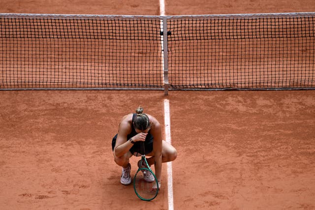 Aryna Sabalenka crouches down on the clay