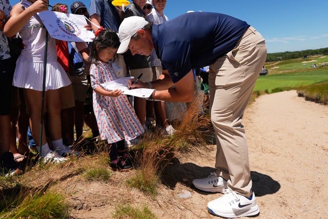 Rory McIlroy bends down to sign an autograph for a young girl