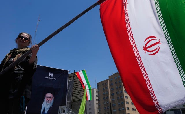 A woman waves an Iranian flag during a pro-government campaign in Tehran