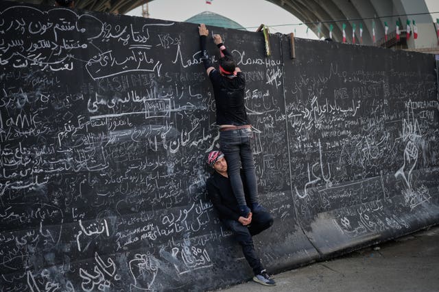 Mourners write messages on a wall during the funeral ceremonies for Ayatollah Ali Khamenei 