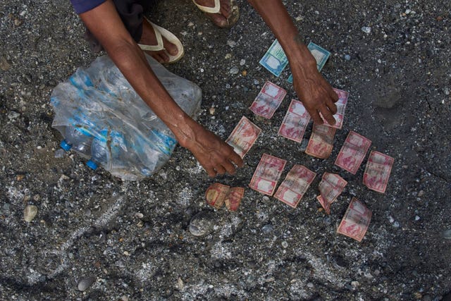 A man salvages money and bottles of mineral water from his house