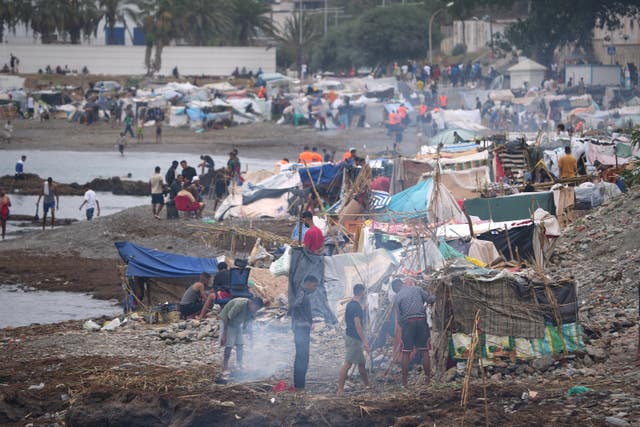 Migrants stand near their tents in the Spanish exclave of Ceuta