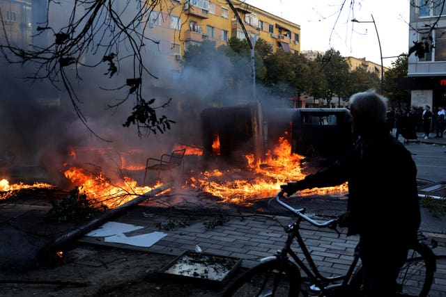 A man passes a burning barricade during clashes in Tirana
